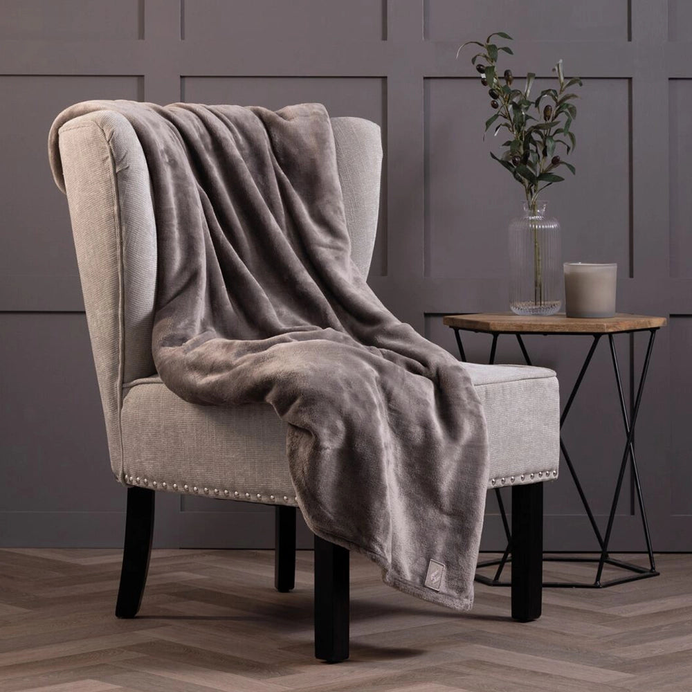 Blanket draped over a chair with a side table and a plant in the background.