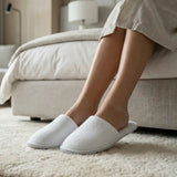 Person wearing white slippers in a cozy living room.