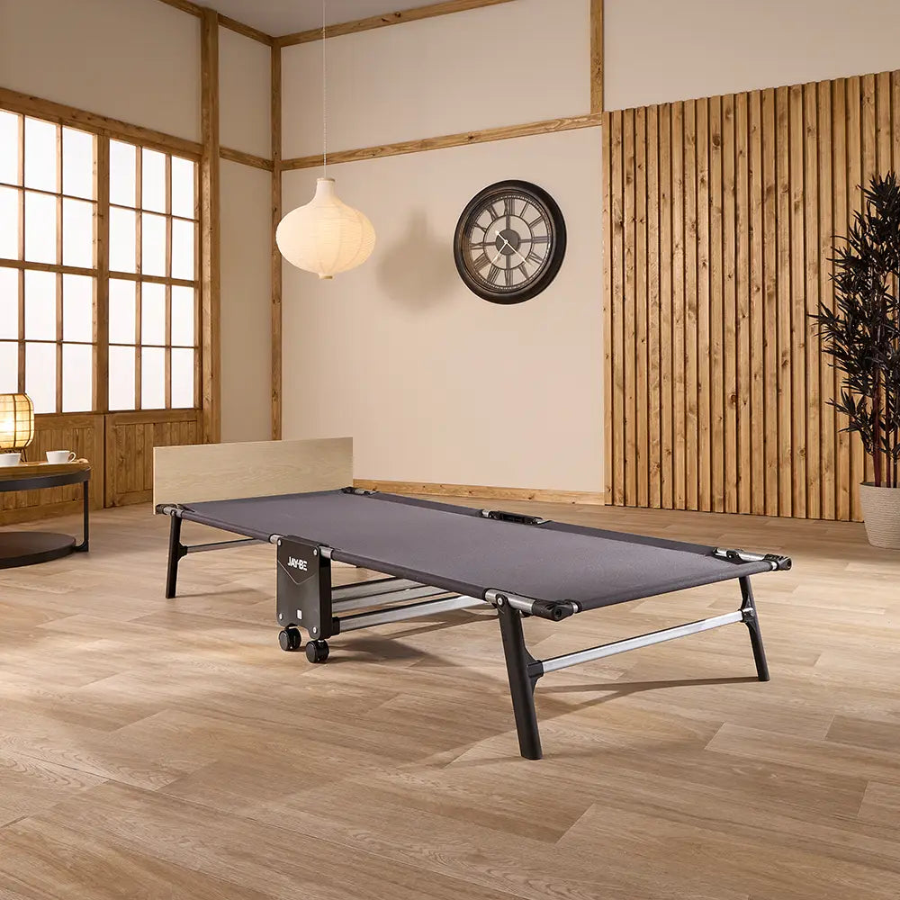 Folding bed in a room with wooden flooring and large windows.