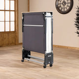 Portable folding bed on wheels in a room with wooden floor and clock on wall.