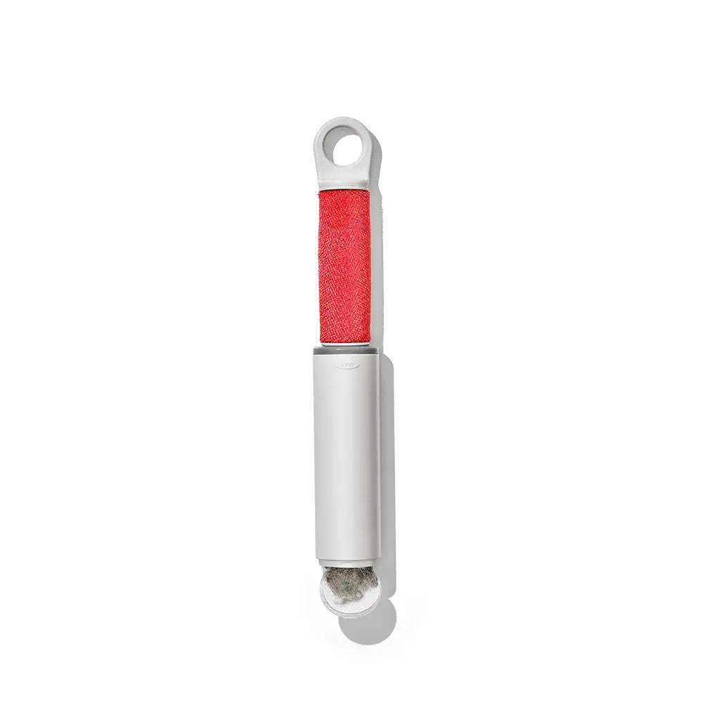 A lint roller with a white plastic body and a textured red lint strip, shown vertically on a clean white background.