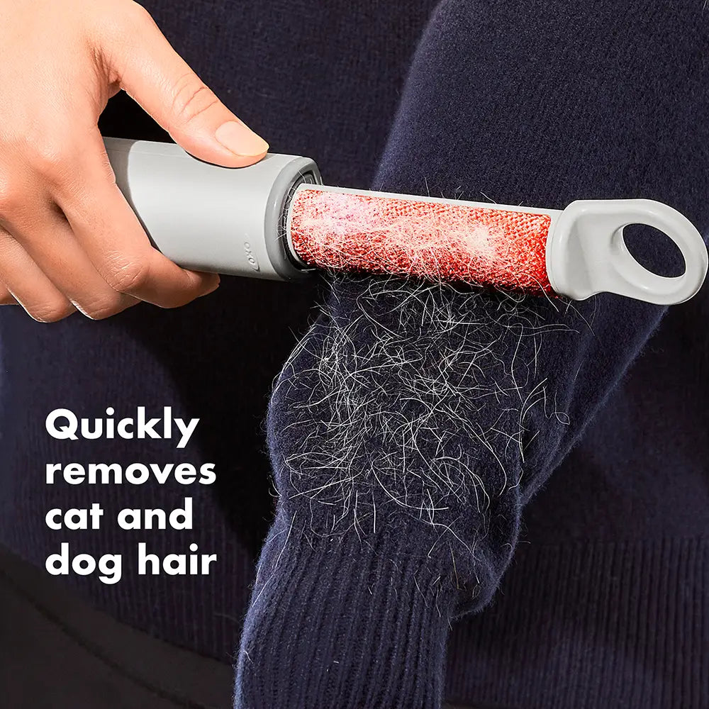 Person using a pet hair remover on a sweater with visible cat and dog hair, text 'Quickly removes cat and dog hair'.