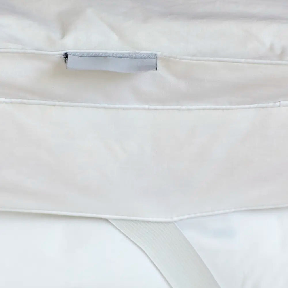 Close-up of Out of Eden Luxury Down Dual Layer Mattress Topper showing box-stitch channels, fabric loop and elasticated strap