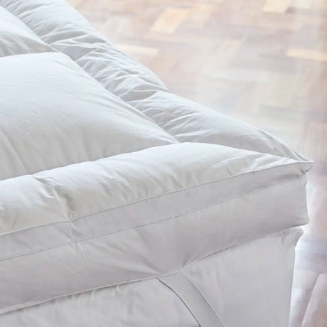 Close-up corner view of Out of Eden Luxury Down Dual Layer Mattress Topper showing box-stitch channels and elasticated strap