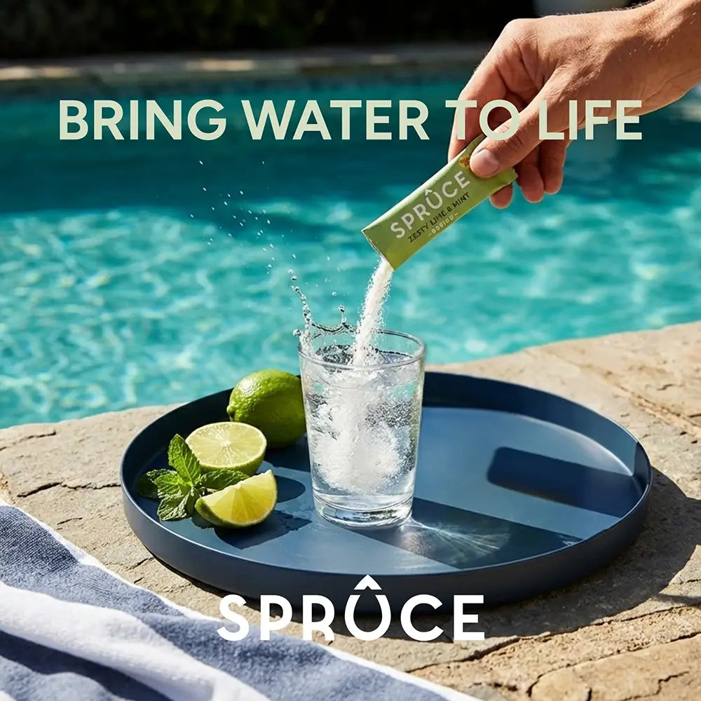 Hand pouring Spruce Zesty Lime & Mint sachet into a glass of water beside a pool, 'Bring Water To Life' tagline