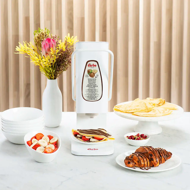 Darbo dispenser on a breakfast table with crepes, croissants and fresh fruit