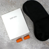 Luxury Sleep Well kit containing Black sleep mask, orange earplugs, and box for the kit that has 'Sleep Well' text on it