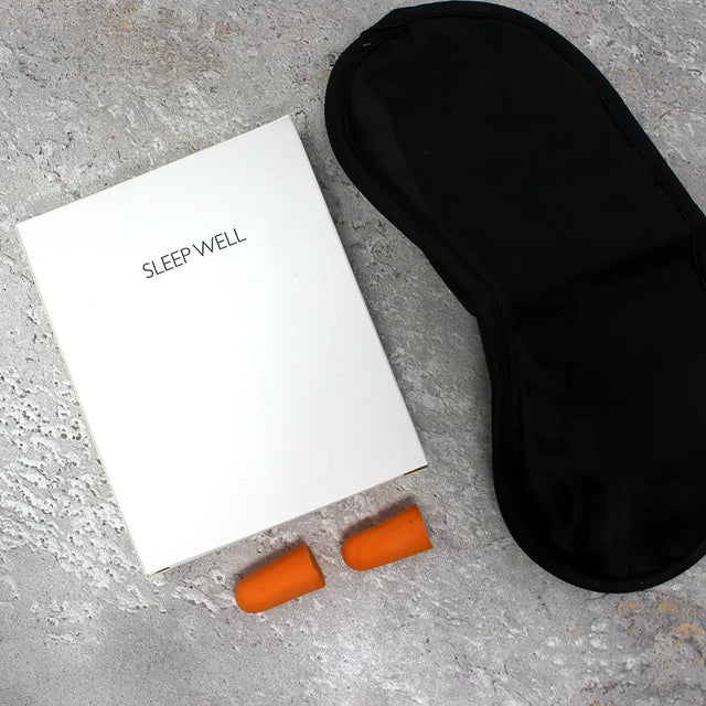Luxury Sleep Well kit containing Black sleep mask, orange earplugs, and box for the kit that has 'Sleep Well' text on it