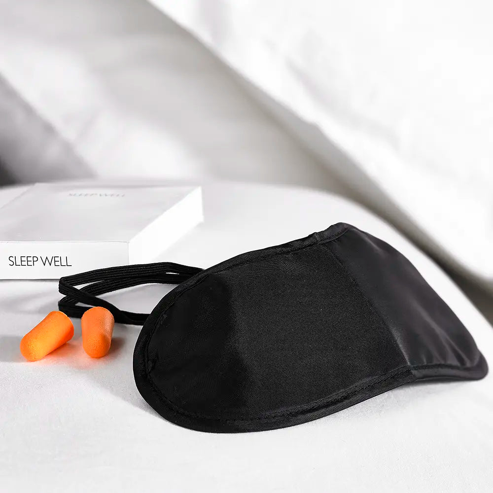 Luxury Sleep Well kit containing Black sleep mask, orange earplugs, and box for the kit that has 'Sleep Well' text on it