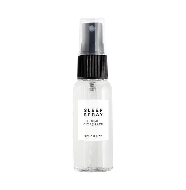 A clear spray bottle labelled 'Sleep Spray' with a black pump dispenser, placed on a white surface, with a cap attached