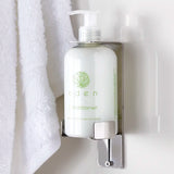 Bottle of Eden Green tea and Lemon zest conditioner on a wall-mounted dispenser with a white towel in the background