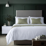 Image featuring Easycare Simplicity Duvet Cover - Neatly made bed with white bedding and green pillows in a bedroom setting.