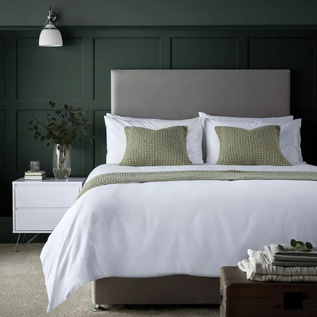 Image featuring Easycare Simplicity Duvet Cover - Neatly made bed with white bedding and green pillows in a bedroom setting.