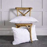 Luxury Just Like Down Eco Pillow - White pillows on a wooden chair against a gray paneled wall.