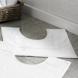 Smallest ever pedestal shaped bathmat in white on a tiled floor