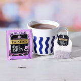 Twinings Earl Grey tea packaging with a cup of tea on a wooden surface.