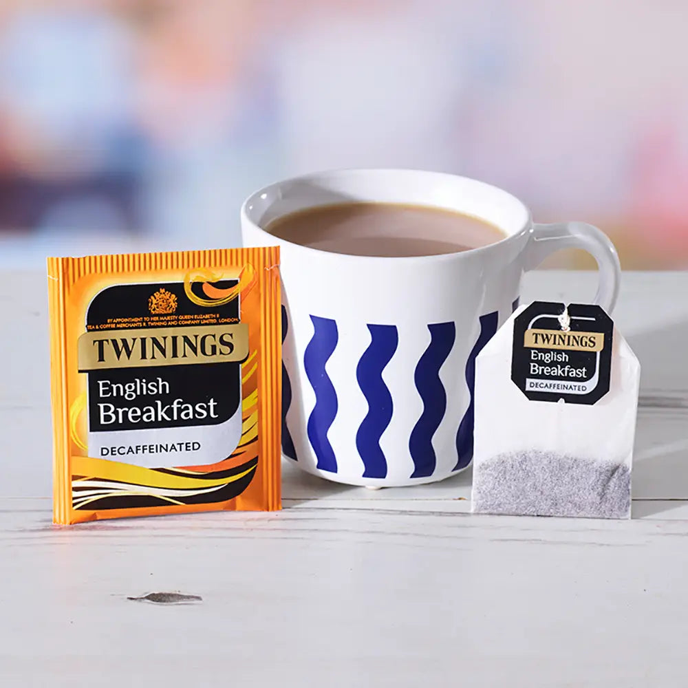 Twinings English Breakfast tea packaging with a cup of tea on a white surface.
