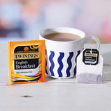 Twinings English Breakfast tea packaging with a cup of tea on a white surface.