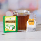 Twinings Pure Peppermint tea packaging with a cup of tea on a wooden surface.