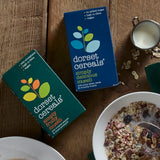 Two boxes of Dorset Cereals on a wooden table with a bowl of cereal.