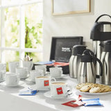 Hotel Coffee setup with cups, yorkshire tea bags, coffee machine, and cookies on a table.