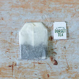 Tea bag with 'Dorset Tea' label on a rustic wooden surface