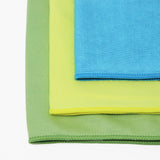 Three microfiber cloths, one green, one yellow and one blue, on a white background.
