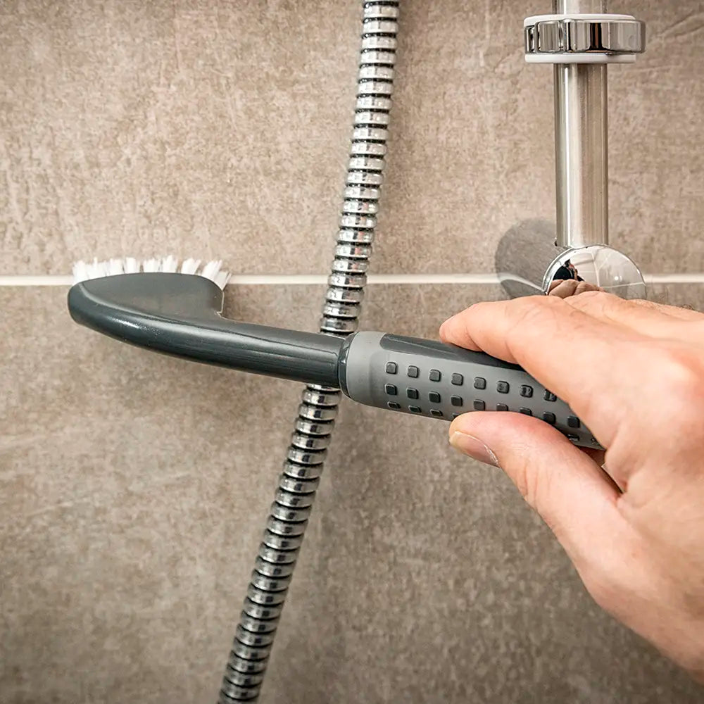 Comfi Grip Tile & Grout Brush - black brush with ergonomic handle and white brussels being used to clean a bathroom