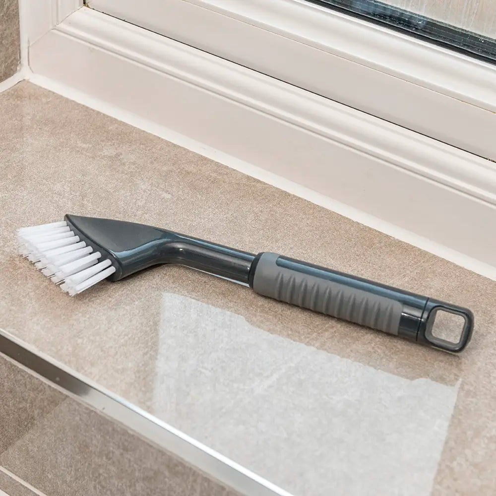 Comfi Grip Tile & Grout Brush - black brush with ergonomic handle and white brussels being used to clean a bathroom