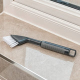 Comfi Grip Tile & Grout Brush - black brush with ergonomic handle and white brussels being used to clean a bathroom