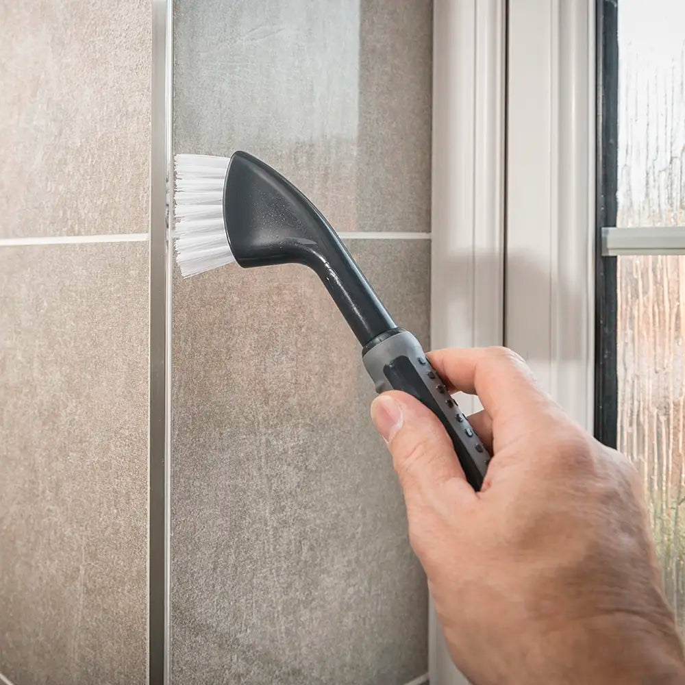 Comfi Grip Tile & Grout Brush being used to clean a shower door.