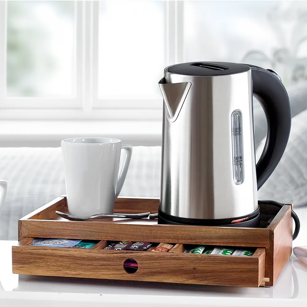 A stainless steel electric kettle on a Acacia Wooden Room Tray with Drawer alongside tea bags and milk bottles.