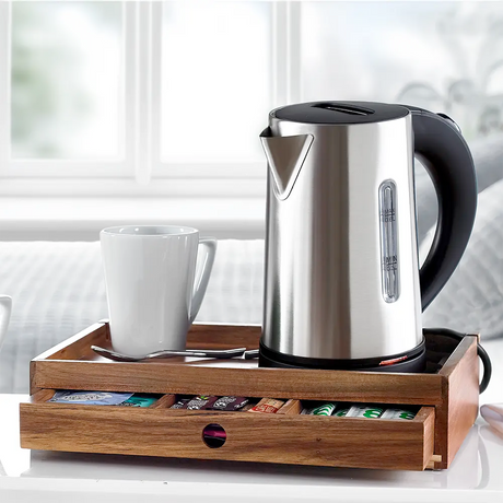 A stainless steel electric kettle on a Acacia Wooden Room Tray with Drawer alongside tea bags and milk bottles.