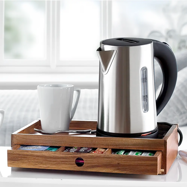 A stainless steel electric kettle on a Acacia Wooden Room Tray with Drawer alongside tea bags and milk bottles.