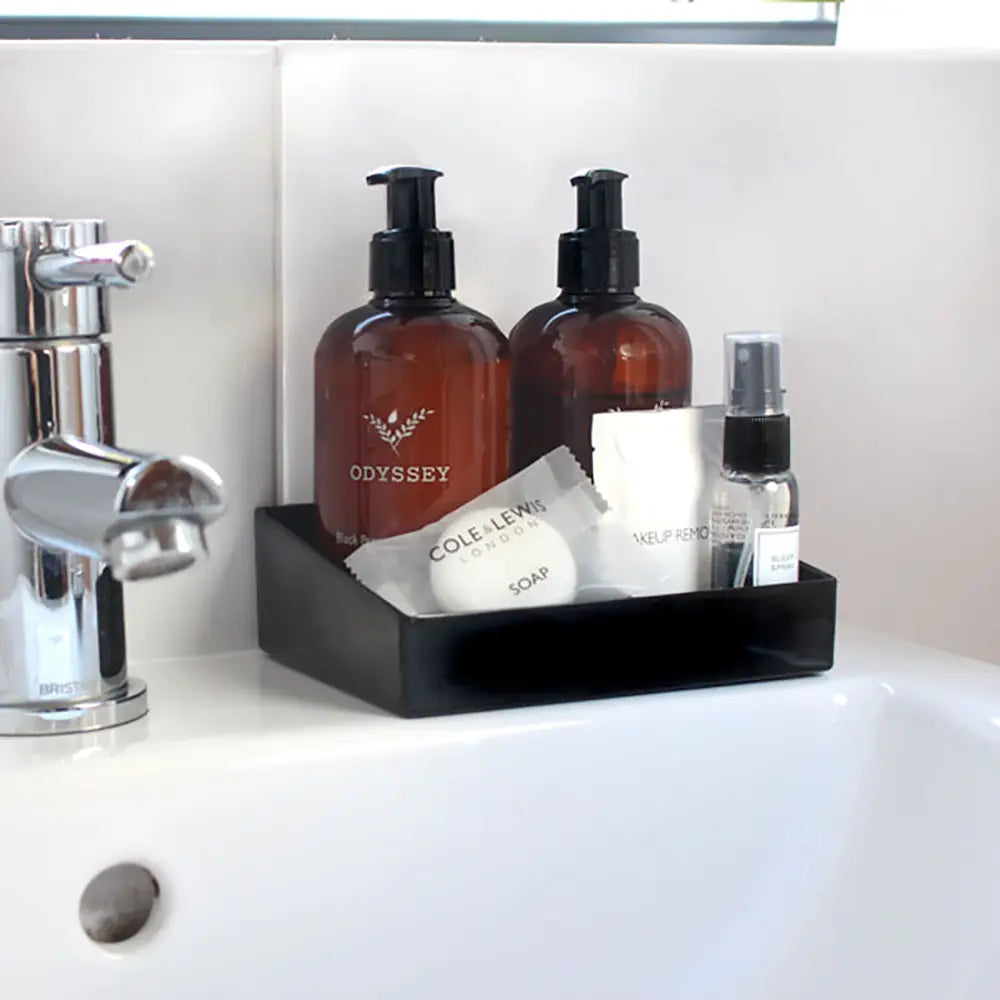 Bathroom sink with Small black Melamine Display Tray with toiletries including bottles and a soap bar 