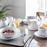 Breakfast setting with white dishes, fruit bowl, and teacup on a wooden table with Heat Resistant Melamine Placemat