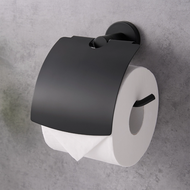 Black toilet paper holder with a roll of toilet paper on a gray wall.