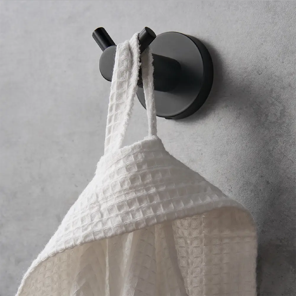 Black wall hook holding a white bathrobe