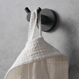 Black wall hook holding a white bathrobe