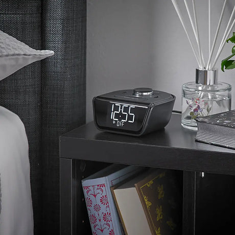 Cubie Wink Hotel Alarm Clock & Charger clock on a nightstand with books and a diffuser in the background