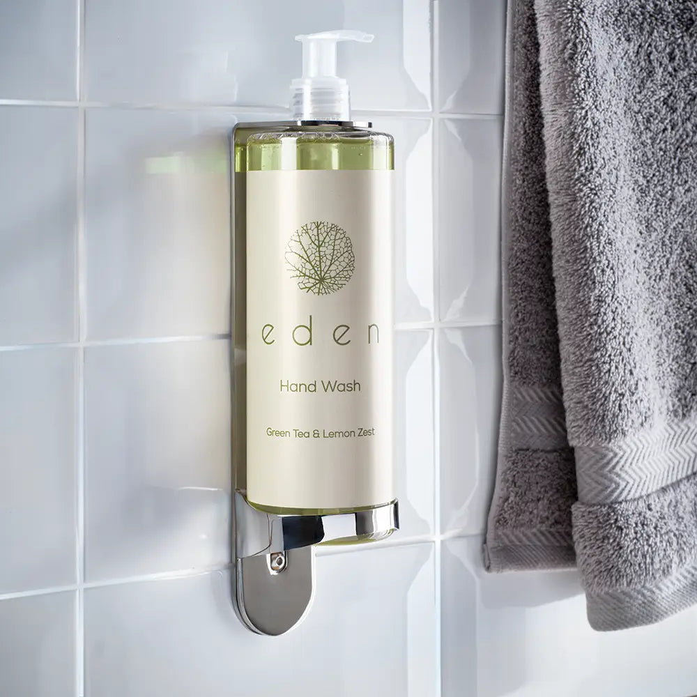 Hand wash bottle labeled 'eden' on a tiled wall with a towel
