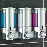  Aviva Triple Soap Dispenser - Three silver shower dispensers labeled 'Shower Gel', 'Conditioner', and 'Shampoo' on a tiled wall.