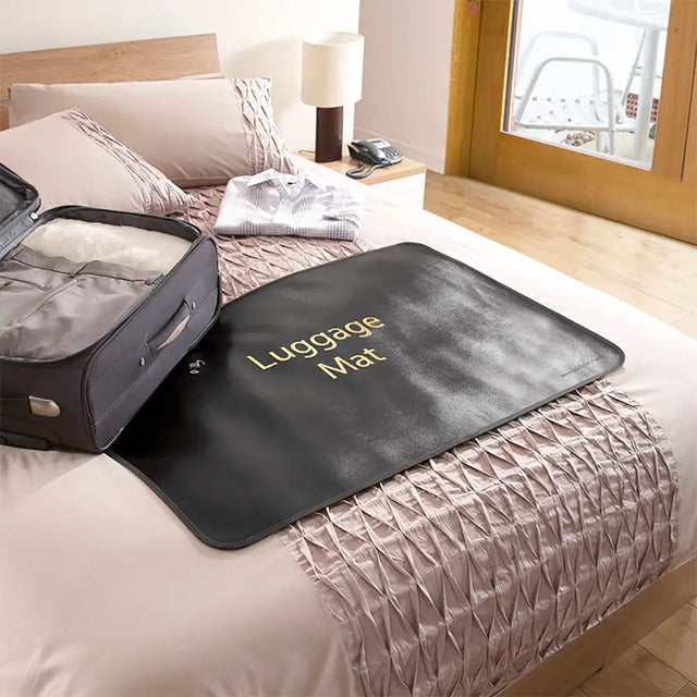 Luggage mat on a bed with an open suitcase next to it, in a bedroom setting.