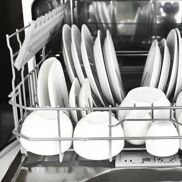 White plates, bowls, and cups stacked in a commercial dishwasher rack